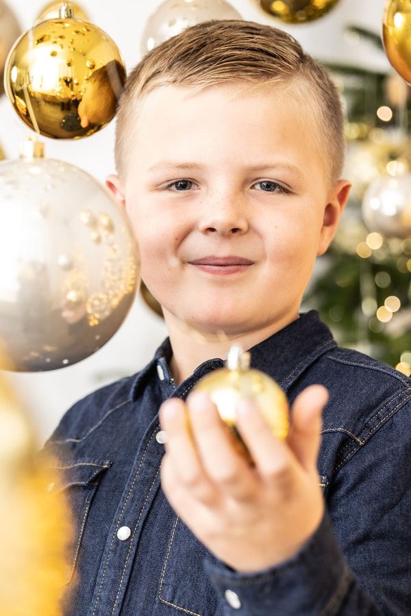 Junge hält eine kleine goldene Kugel in die Kamera