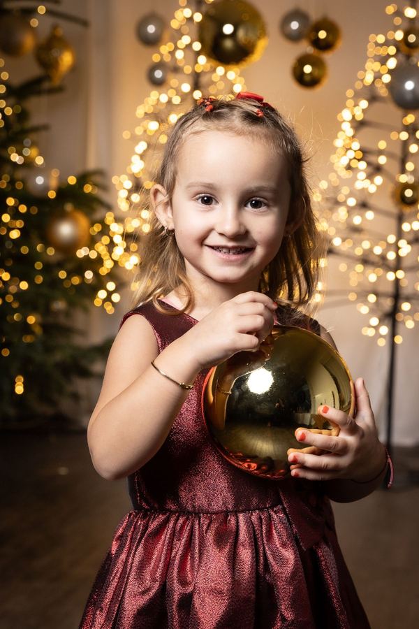 Mädchen im roten Samtkleid mit goldener Kugel